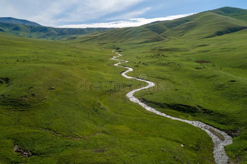 From the height of the green river valley in the mountains at the height of the clouds in the morning. River and green meadows fro