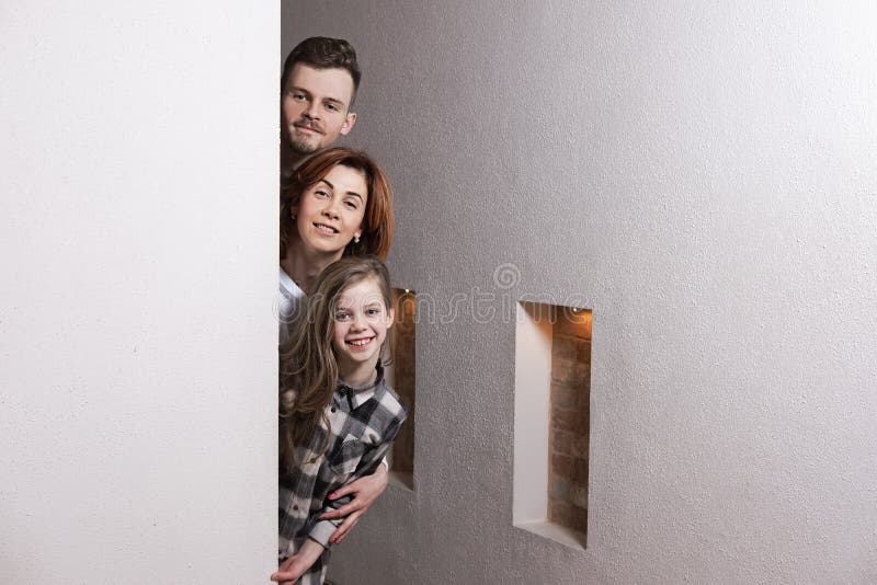 Tricky family peeks around the corner of the wall at home. Tricky family peeks around the corner of the wall at home