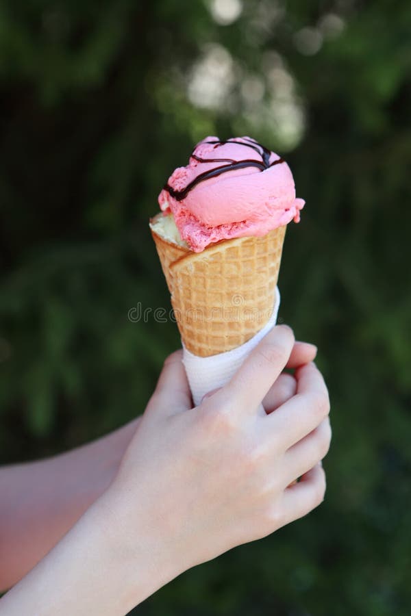 Helado en las manos de los niños Helado de fresa en un cono de la galleta