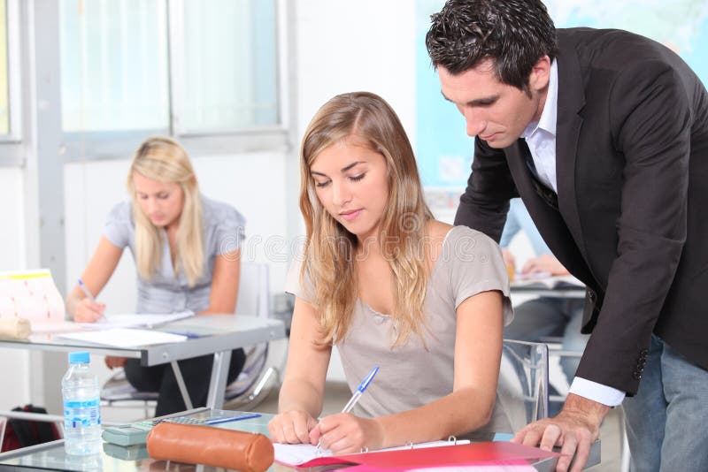 Helfende Kursteilnehmer des Lehrers lizenzfreies stockfoto Helfende Kursteilnehmer des Lehrers lizenzfreies stockfoto