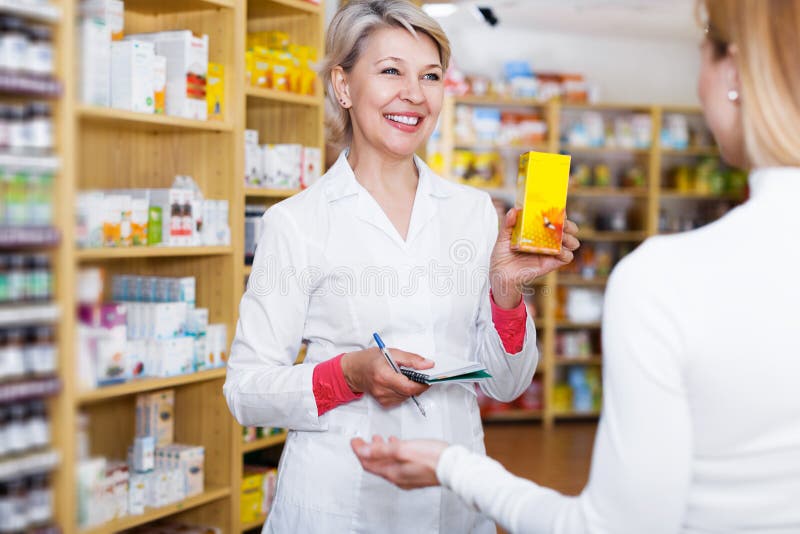 Smiling adult seller helping customer to choose care products in specialized shop. Smiling adult seller helping customer to choose care products in specialized shop