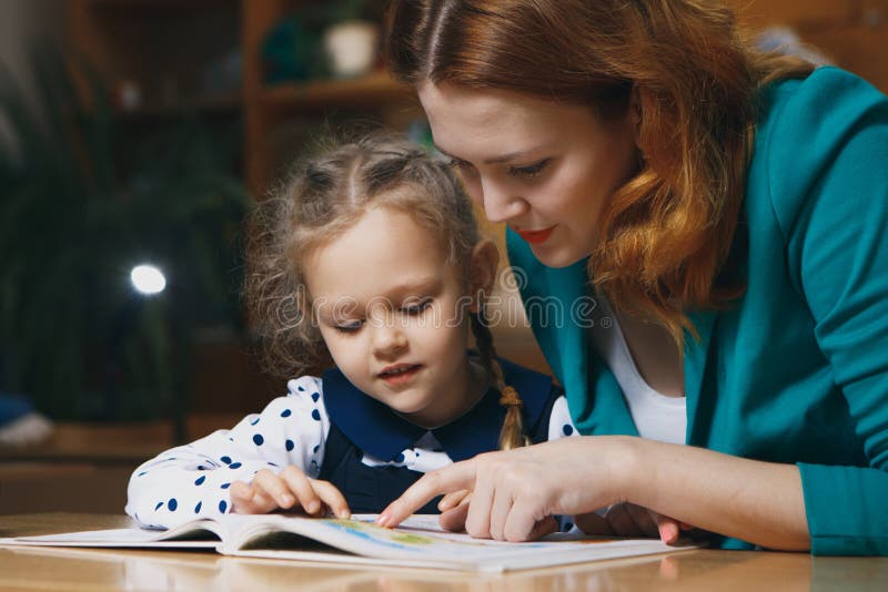 Helfendes Kind der Mutter nach der Schule Vorschüler, der Hausarbeit mithilfe des Tutors tut unterrichtendes Hauptkonzept stockfotografie