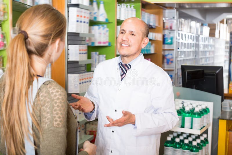 Professional pharmaceutist in drugstore helping girl to choose medication. Professional pharmaceutist in drugstore helping girl to choose medication
