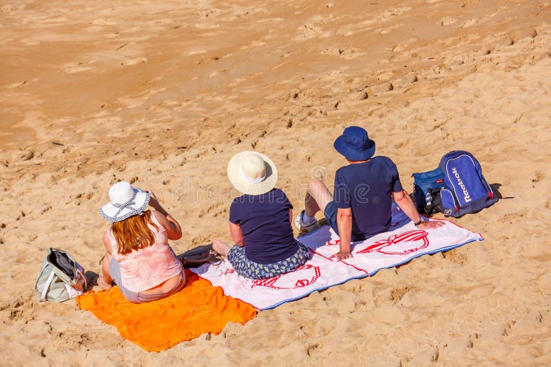Helgon-Jean de Luze, Frankrike - Sept 28, 2016: familjsammanträde på strandhanddukar i sanden Tre personer, en man och två kvinno royaltyfria foton Helgon-Jean de Luze, Frankrike - Sept 28, 2016: familjsammanträde på strandhanddukar i sanden Tre personer, en man och två kvinno royaltyfria foton