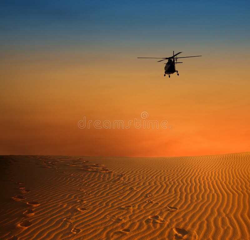 Sunset scene with silhouette of a helicopter over dersert