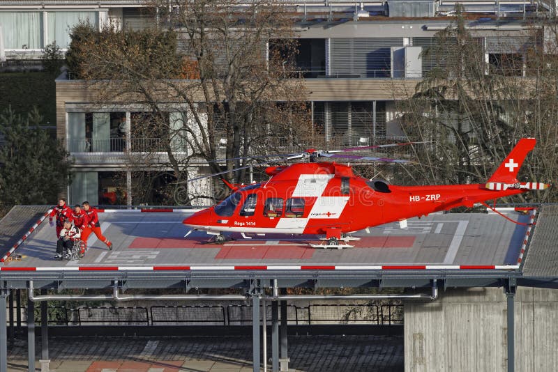 THUN, SWITZERLAND - JANUARY 1, 2014: Helicopter and patient on the hospital roof in Thun City. Thun is a city in the canton of Bern in Switzerland. There is a view of Bernese Alps.