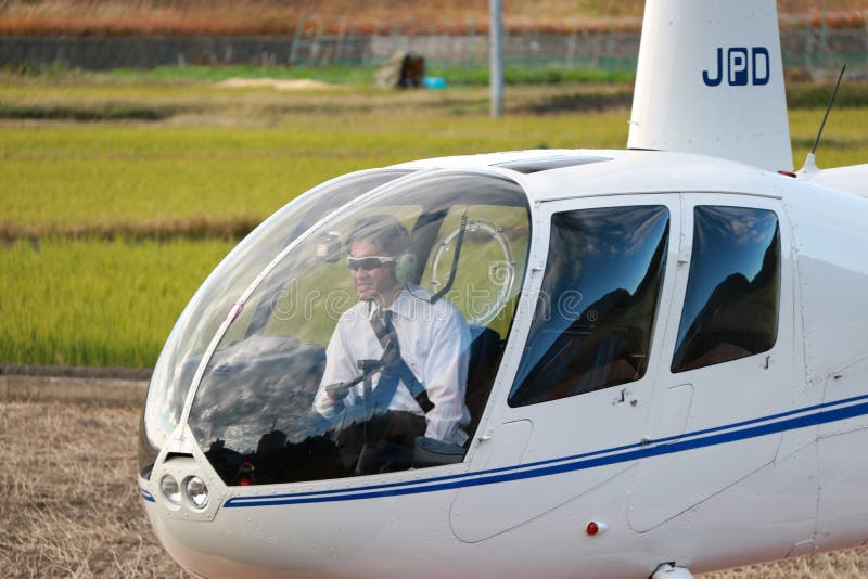 Helikopterpilot i lopphelikoptern JA002R - ROBINSON R44 som ÄR KORPSVART från Robinson Helicopter Company arkivfoto Helikopterpilot i lopphelikoptern JA002R - ROBINSON R44 som ÄR KORPSVART från Robinson Helicopter Company arkivfoto
