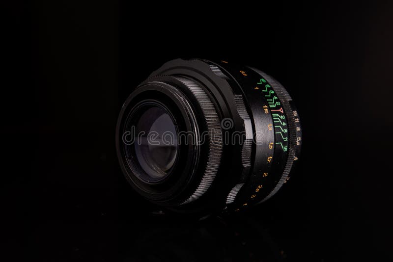 Kyiv, Ukraine, 03.30.2021. Helios lens on the black background. A classic optical vintage lens with reflection. Optics, camera tool, old, retro, focus, scale. Kyiv, Ukraine, 03.30.2021. Helios lens on the black background. A classic optical vintage lens with reflection. Optics, camera tool, old, retro, focus, scale