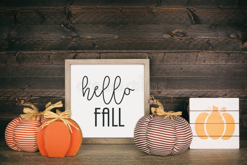 Hello fall sign with rustic pumpkin home decor on a shelf against dark wood stock image