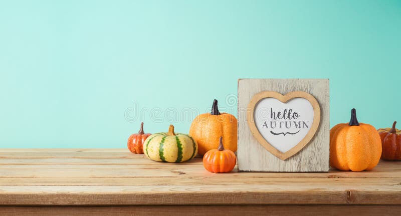 Hello najaarsconcept met fotoframe en pompoendecor op houten tafel boven blauwe achtergrond. de groet van het herfstseizoen