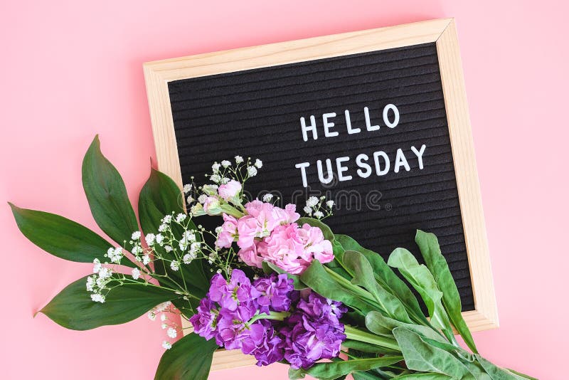 Hello Tuesday text on black letter board and bouquet colorful flowers on pi...