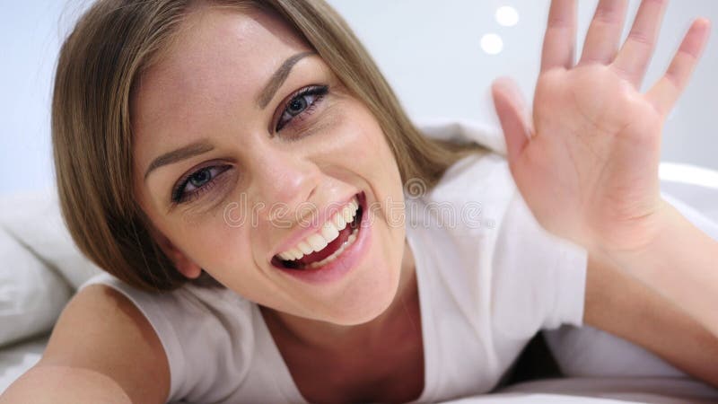 Hello, Welkom hetende Vrouw in Bed Golvende Hand, Online Videopraatje stock afbeelding Hello, Welkom hetende Vrouw in Bed Golvende Hand, Online Videopraatje stock afbeelding