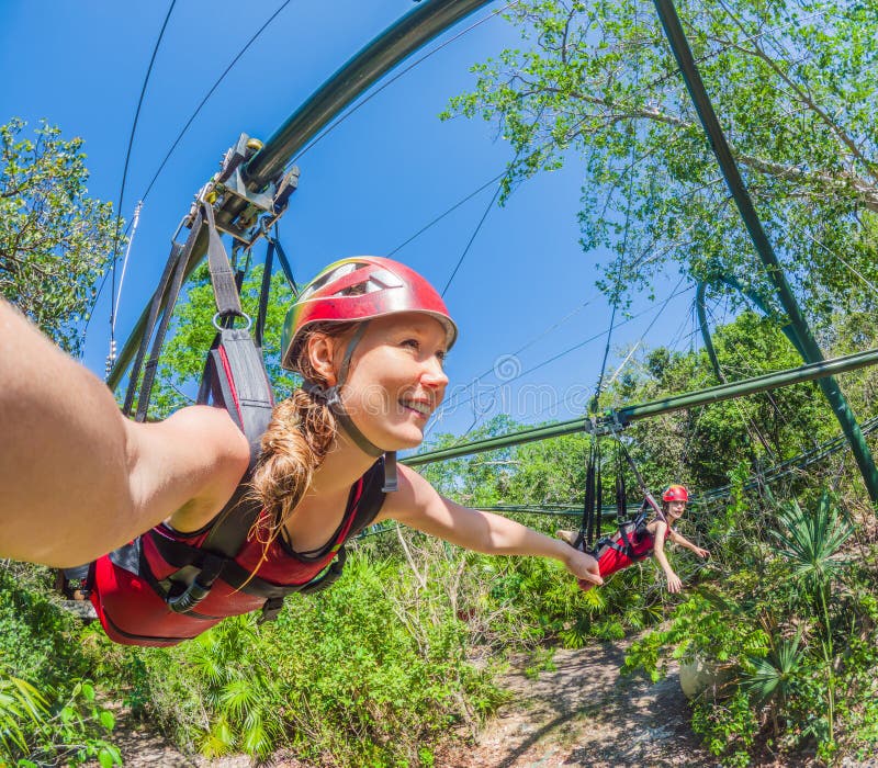 Helmfrau, die auf einer Zipline über einen üppigen tropischen Park fliegt. spannendes Abenteuer inmitten der Natur perfekt für Öko stockfotos
