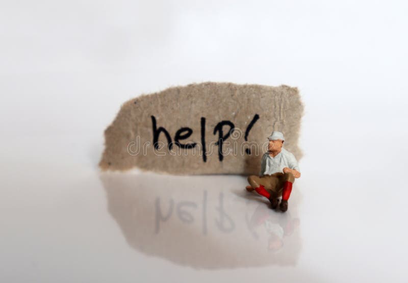 The `help! ` text written on a torn cardboard. A stack of coins and a miniature man sitting. stock images
