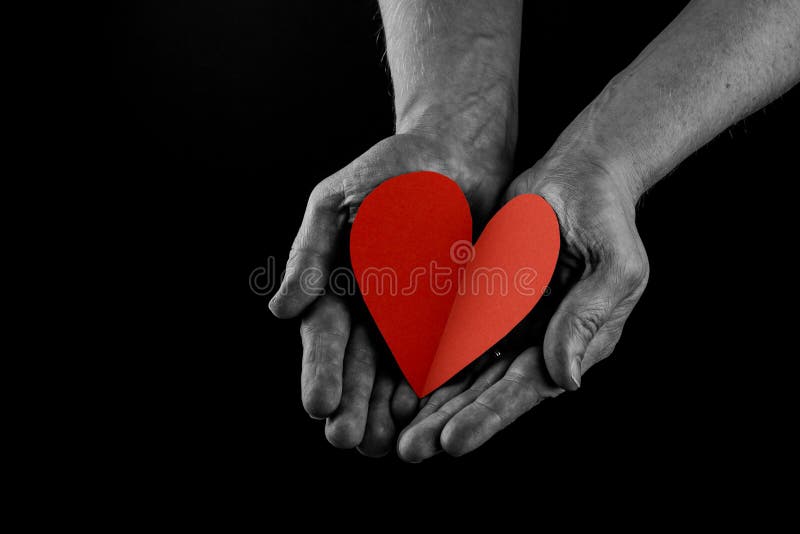 Helping hand concept, Man`s hands palms up holding a Red Heart, giving love, care and support, reaching out. side view