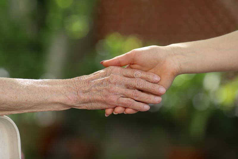 Young caregiver holding seniors hands. Helping hands, care for the elderly concept royalty free stock photos Young caregiver holding seniors hands. Helping hands, care for the elderly concept royalty free stock photos