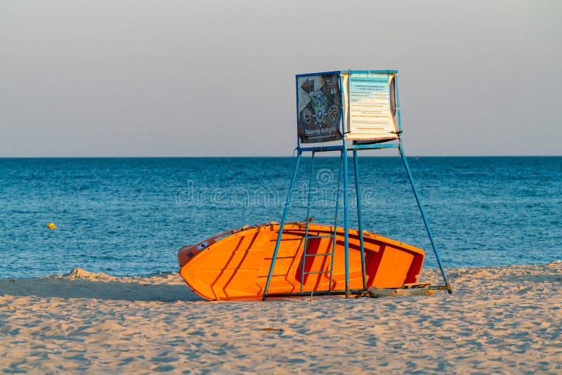 Helpoland 08012021 : Skyddsstativ med orange båt under den på en strand i gyllene timsljus. tom strand på arkivbild