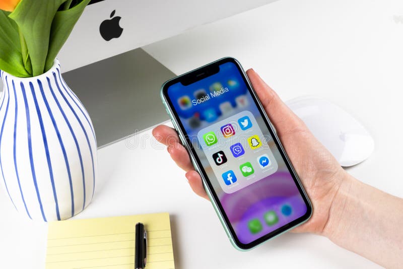 Apple iPhone 11 in woman hands with icons of social media facebook, instagram, twitter, snapchat application on screen. Social med