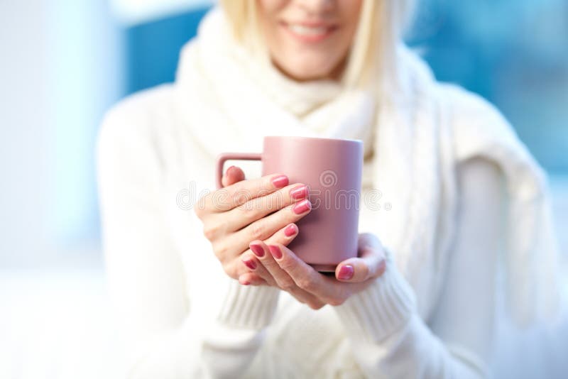 Photo of pink porcelain cup in female hands. Photo of pink porcelain cup in female hands