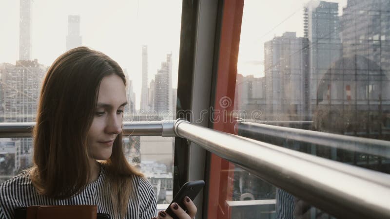 hembra turística europea 4K en cabina del tranvía del aire Empresaria hermosa con smartphone en la isla de Nueva York funicular