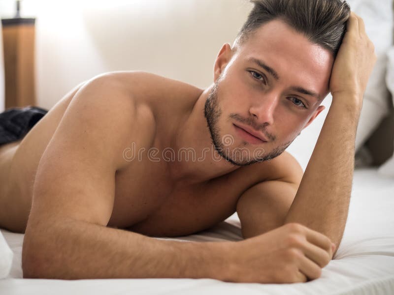 Hemdloses sexy männliches Modell, das allein auf seinem Bett liegt