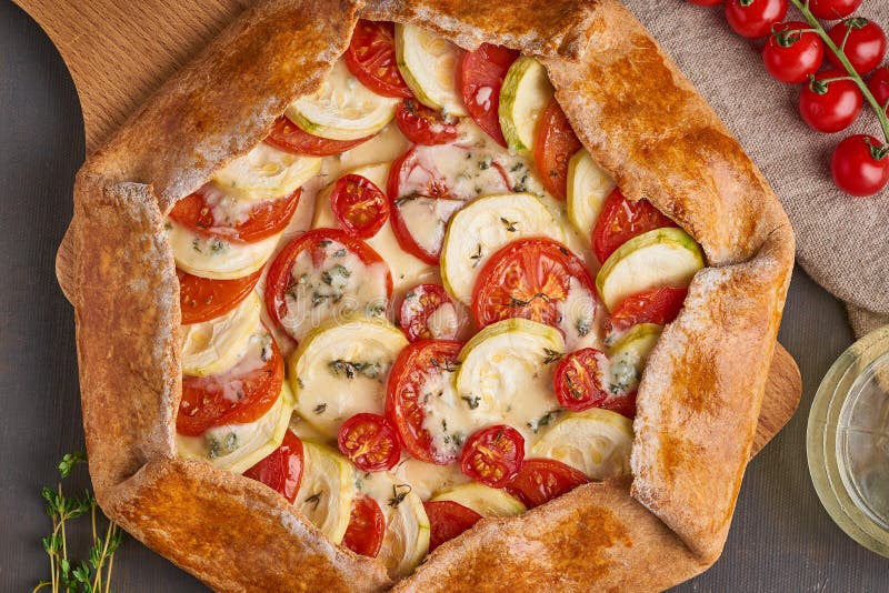 Hemlagad galette med gr?nsaker, wholegrain paj med tomater, zucchini, ost B?sta sikt, slut upp M?rk brun tabell royaltyfri fotografi Hemlagad galette med gr?nsaker, wholegrain paj med tomater, zucchini, ost B?sta sikt, slut upp M?rk brun tabell royaltyfri fotografi