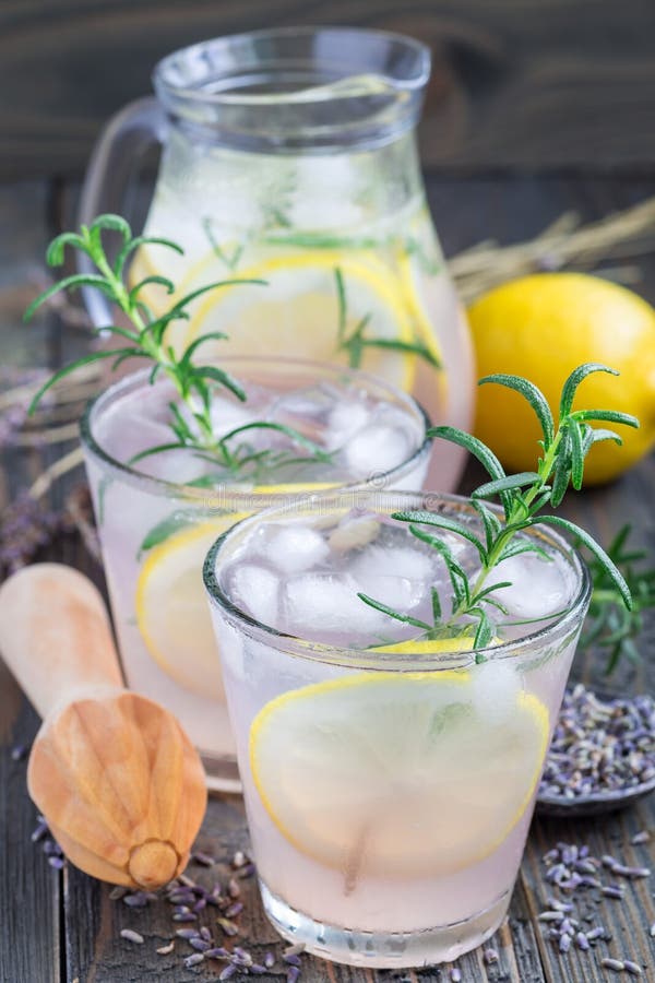 Hemlagad lemonad med lavendel, nya citroner och rosmarin på trätabellen, lodlinje royaltyfria bilder Hemlagad lemonad med lavendel, nya citroner och rosmarin på trätabellen, lodlinje royaltyfria bilder