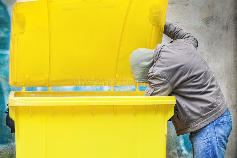 Homeless near yellow garbage container. Homeless near yellow garbage container