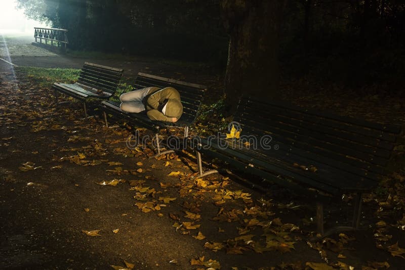 Homeless sleeping on a bench under the strong light of a lamp. Homeless sleeping on a bench under the strong light of a lamp