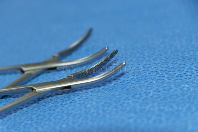 Closeup Image Of Hemostats Artery Forceps Tip In Blue Background. Selective Focus