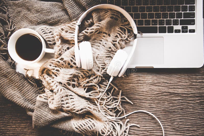 Hemtrevlig vinterbakgrund, kopp av varmt kaffe med marshmallowen och headphonemusik, varm stucken tröja, arbetsutrymmebärbar dato royaltyfria foton