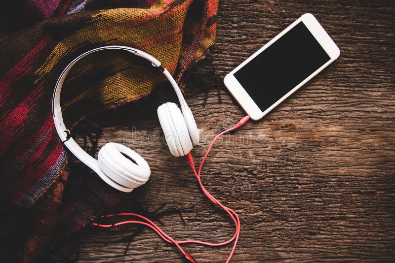 Hemtrevlig vinterbakgrund, koppen av varmt kaffe med marshmallowen och headphonemusik, värme den stack tröjan royaltyfri foto