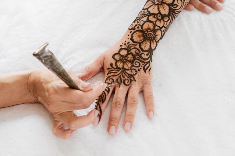 Artista aplicando tatuagem de henna mehndi na mão feminina