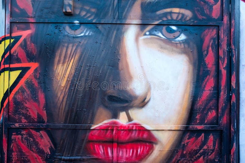 Her eyes are expressive, set beneath arched eyebrows, with one obscured by shadow. Her lips are painted a bold red. The image is framed by a mix of blues, blacks, and reds, creating a dramatic contrast. The use of colour and shading gives the piece a lifelike quality. A star-like shape is partially visible on the left, adding a dynamic element to the composition. Dynamic colour stock images, royalty-free photos and pictures