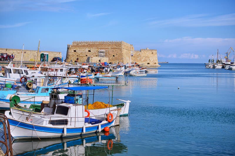Heraklion, Crete - Greece. Traditional fishing boats in front of the fortress Koules castello a mare at the old port in Heraklio