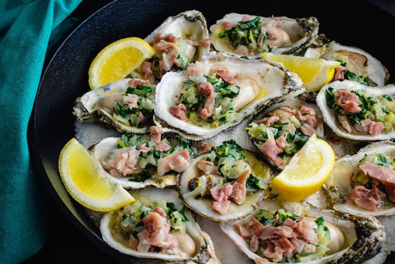 Herb Butter Oysters with Prosciutto in a CastIron Skillet Stock Photo