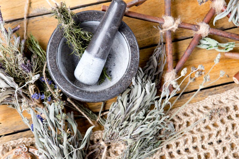 Herb Witch workings with Mortar and Pestle, branch pentagram and dried herb bundles on wooden background