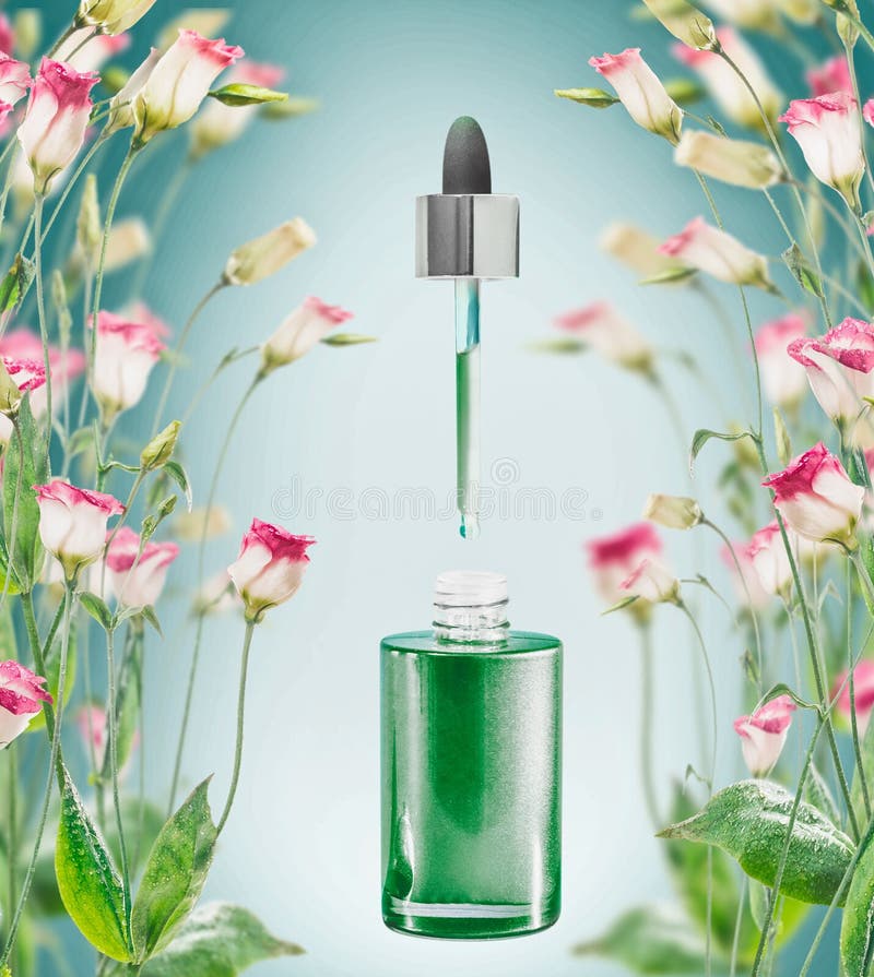 Herbal facial serum bottle with pipette and flowers plats on blue background