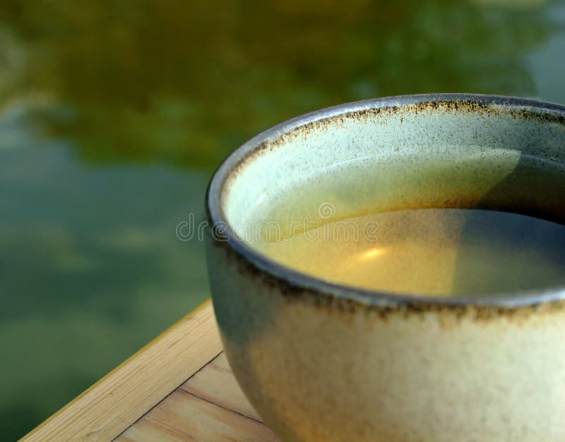 Primo piano di una tazza di erbe, tè verde, seduto su un tavolo di legno.