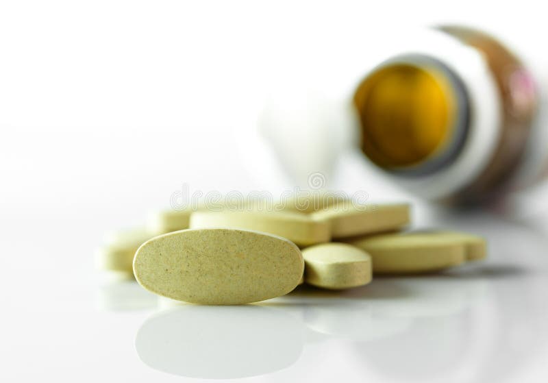 Herbal tablets , Medicine out of pill bottle on white background royalty free stock photos