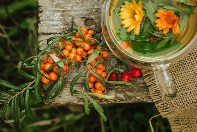 Herbal tea of mint, calendula and sea buckthorn berries in a glass transparent cup on a brown wooden table 3