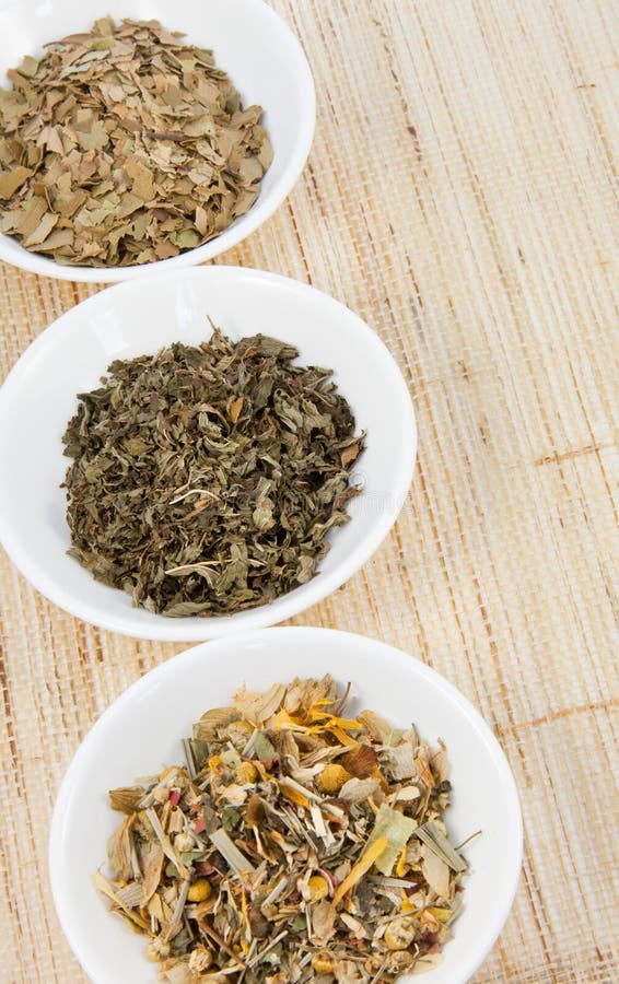 Herbal teas in small white bowls on natual matting