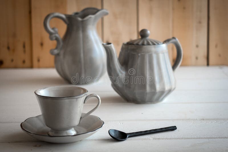 Herbata set jest Szary na drewnianym tle Teapot, creamer, filiżanka i spodeczek na stole, Ceramiczny kitchenware