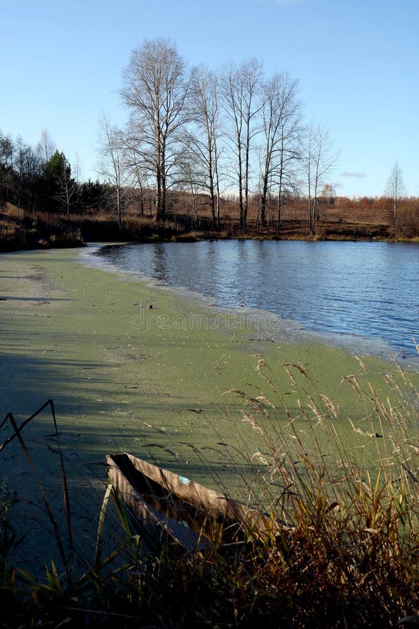 Herbstlandschaft mit einem Teich und einem defekten Boot stockfotografie Herbstlandschaft mit einem Teich und einem defekten Boot stockfotografie
