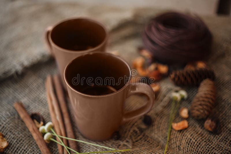 Autumn composition: 2 cups, cinnamon, pinecones on the canvas cloth. Autumn composition: 2 cups, cinnamon, pinecones on the canvas cloth.