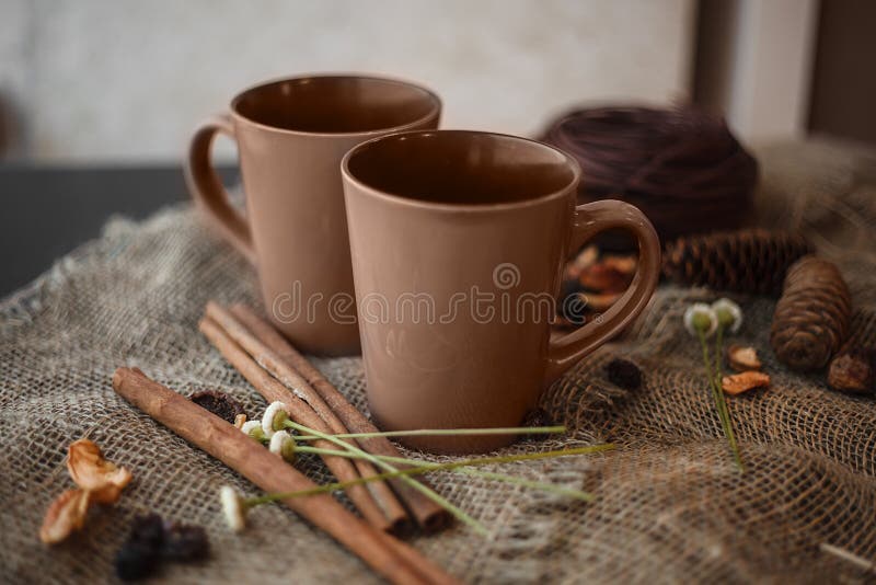 Autumn composition: 2 cups, cinnamon, pinecones on the canvas. Autumn composition: 2 cups, cinnamon, pinecones on the canvas