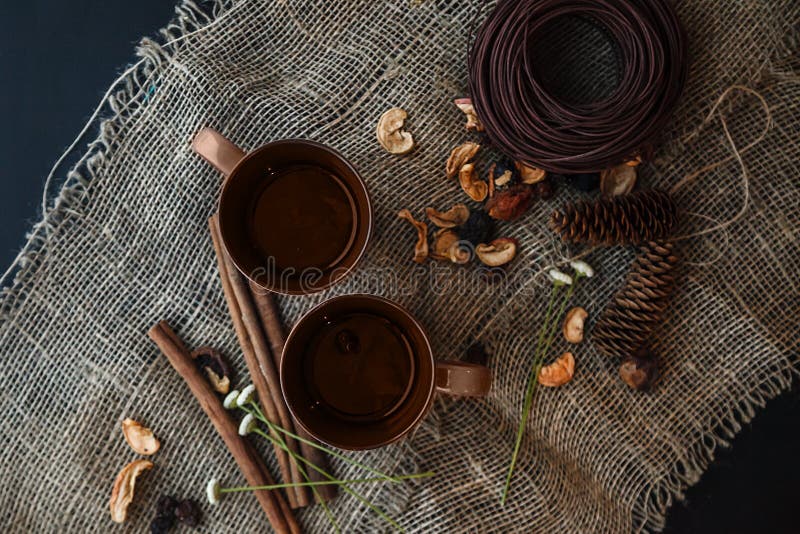 Autumn composition: 2 cups, cinnamon, pinecones on the canvas cloth. Autumn composition: 2 cups, cinnamon, pinecones on the canvas cloth.