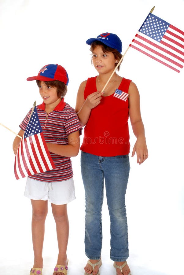 Two elementary girls in patriotic colors waving American flags. They're ooking off into the distance as if waiting for a parade. Isolated on white. Two elementary girls in patriotic colors waving American flags. They're ooking off into the distance as if waiting for a parade. Isolated on white.