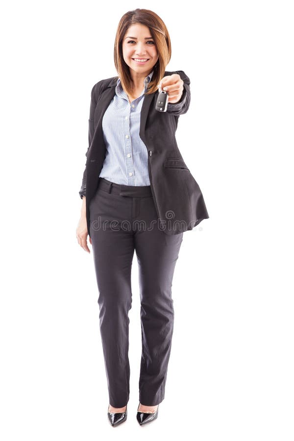 Full length view of a female sales executive of a car dealership handing over the keys to a new car. Full length view of a female sales executive of a car dealership handing over the keys to a new car