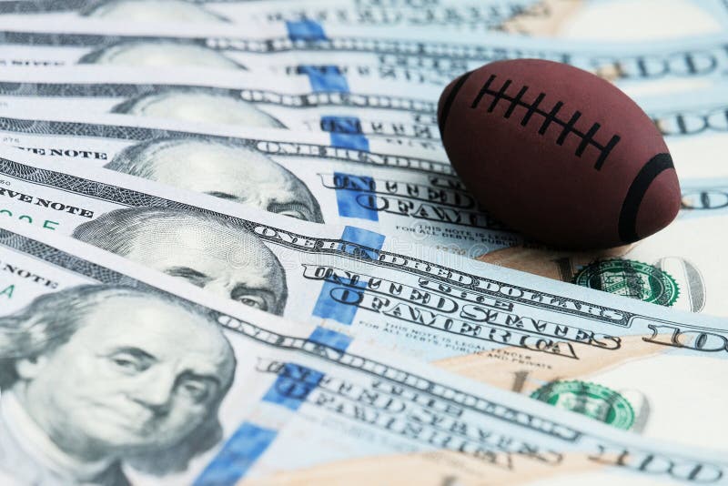 Herinneringsbal voor het spelen van rugby of Amerikaanse voetbal op de bankbiljetten van de V.S. Het concept corruptie of sporten royalty-vrije stock afbeelding Herinneringsbal voor het spelen van rugby of Amerikaanse voetbal op de bankbiljetten van de V.S. Het concept corruptie of sporten royalty-vrije stock afbeelding